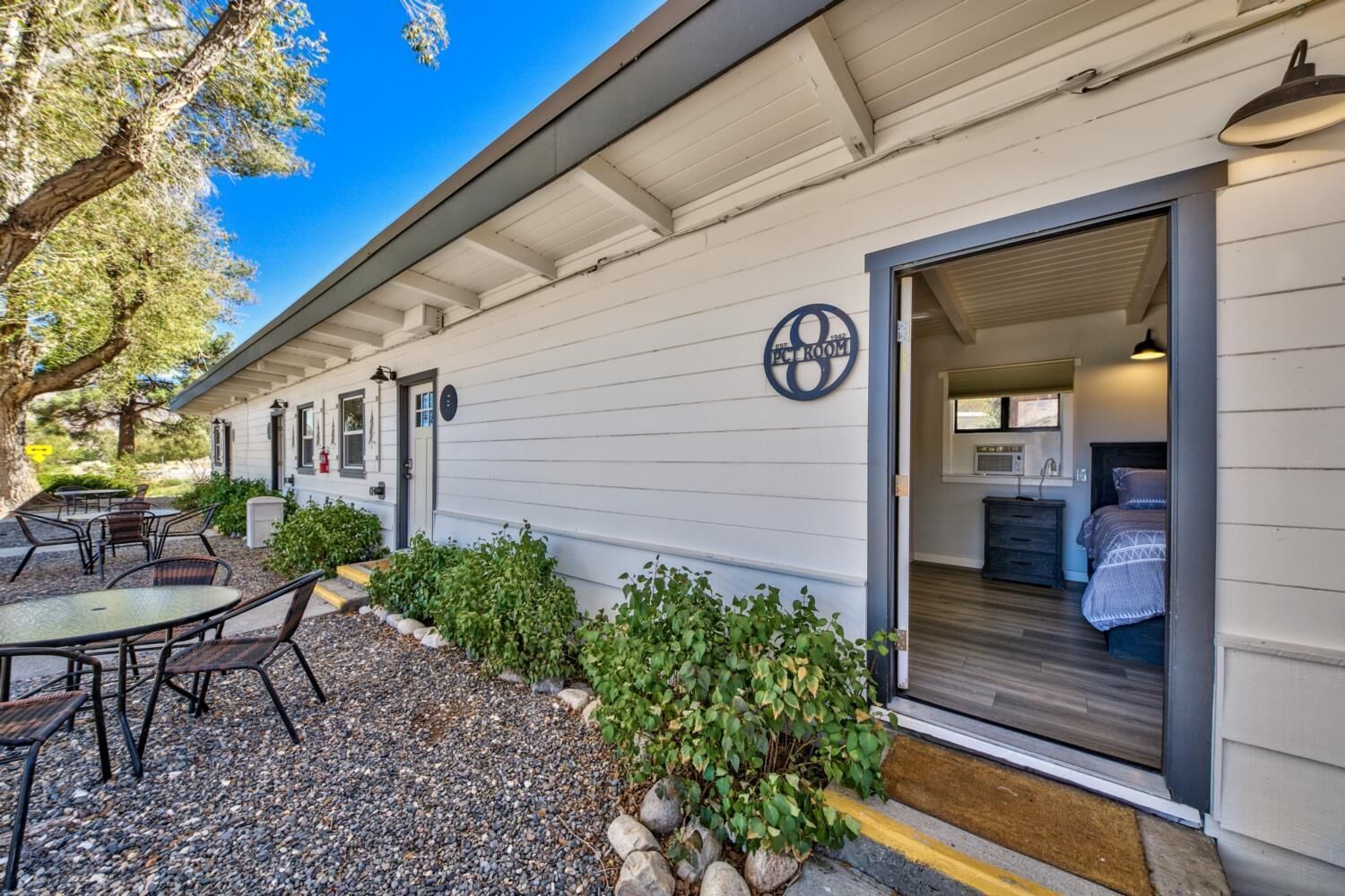A motel with a patio area, a bed in the room, and a sign indicating the room number.