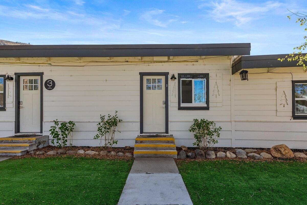 A single-story house with a front porch, numbered doors, and a small garden area.