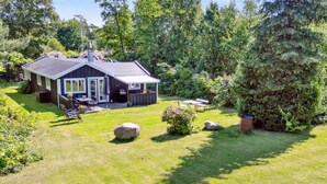 Een huis met terras, patio en gazon.