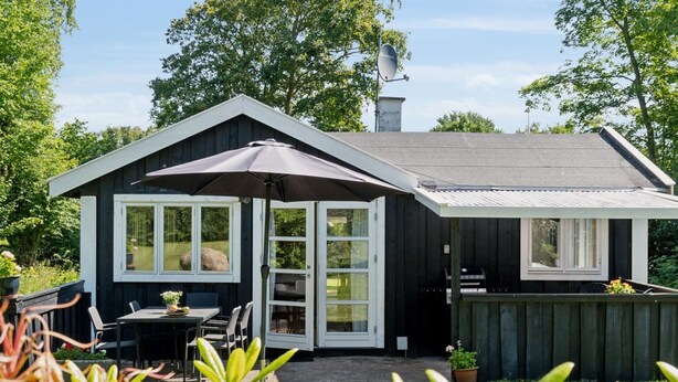 Een huis met een overdekte patio, een omheinde achtertuin en een schotelantenne.