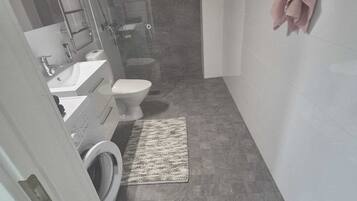 Un bagno compatto con servizi igienici, lavabo e lavatrice.
