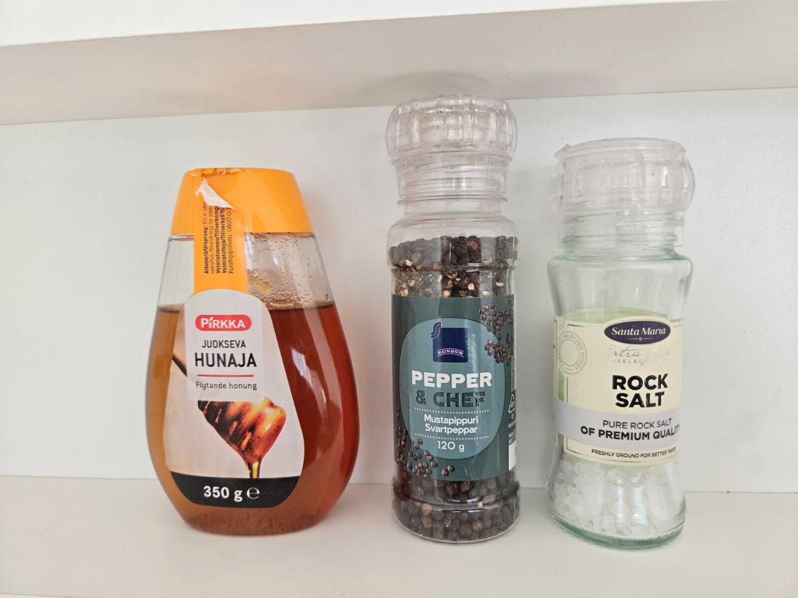 Three condiment bottles: a 350g bottle of Pirkka Hunaja, a 120g bottle of Rainbow Pepper & Chef, and a 500g bottle of Santa Maria Rock Salt.