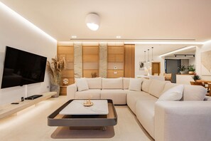 A modern living room with a sectional sofa, a coffee table, and a flat-screen TV.