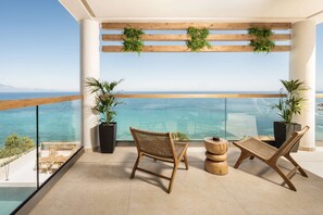 A balcony with wicker chairs, potted plants, and a view of the sea.