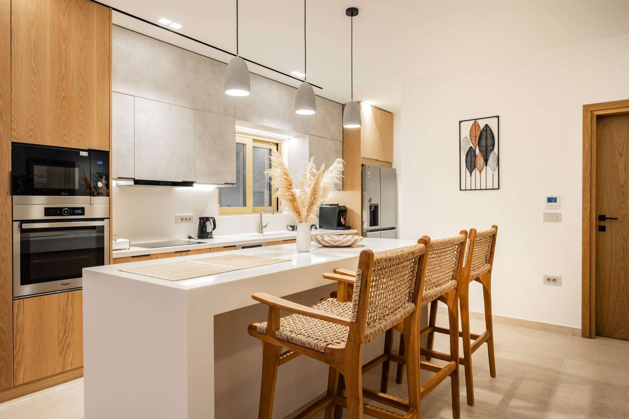 Una cucina moderna con mobili in legno, elettrodomestici in acciaio inox, un'isola centrale con sgabelli da bar e un elemento decorativo a parete.