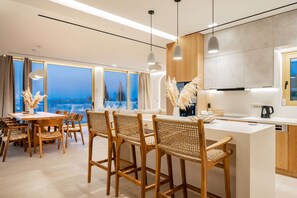 A modern kitchen with a large island, bar stools, and a view of the ocean.