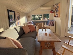 Um quarto aconchegante com uma mesa de madeira, um sofá estofado e uma janela com vista para o verde.