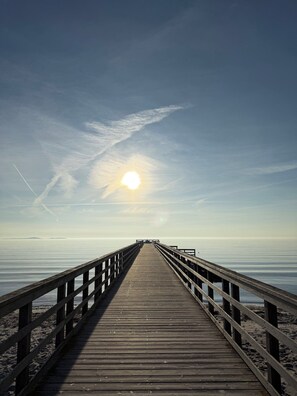 Un muelle de madera se adentra en aguas tranquilas bajo un cielo despejado.