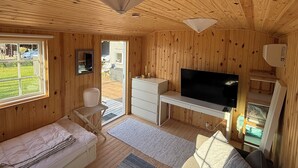 A wooden cabin interior with a TV, a desk, a chair, and a bed. - Cosy summer house at Kobæk Strand (Skælskør)