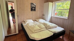 A bedroom with a bed, a wardrobe, a window, and a door.