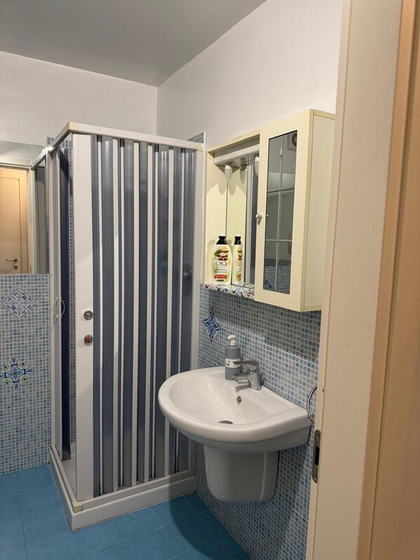A bathroom with a shower, a sink, and a mirror.