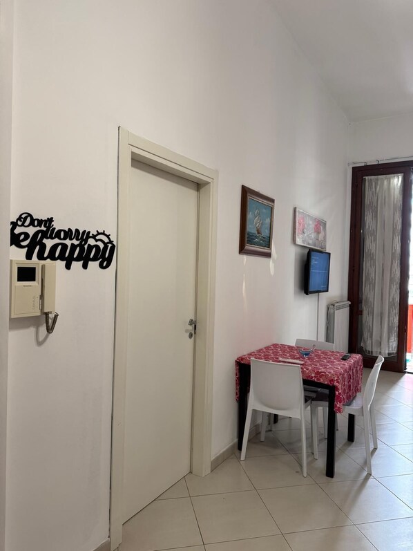 A dining area with a table set for two, a door, and a wall-mounted phone.