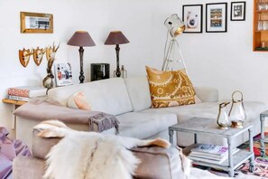 Una sala de estar con sofá, lámparas, una mesa de centro y elementos decorativos.