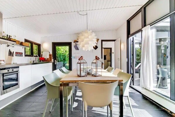 A modern kitchen with a built-in oven and a dining area with a table and chairs.