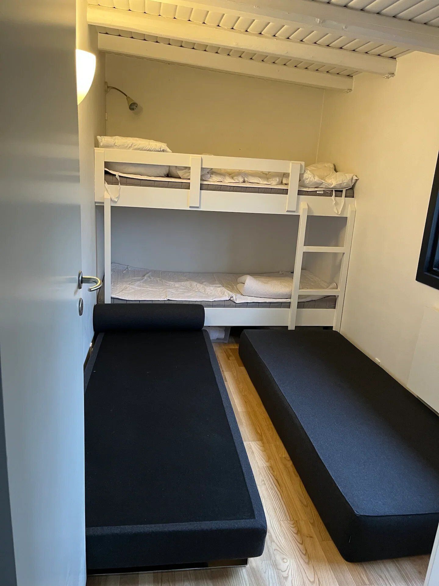 Une chambre avec un lit superposé, un matelas escamotable et une fenêtre.