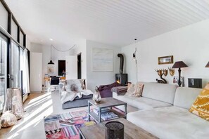 Una sala de estar moderna con chimenea, un sofá, una mesa de centro y un comedor al fondo.