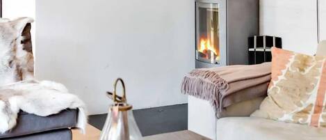 A cozy living room with a modern fireplace, a plush sofa, and a decorative lamp.