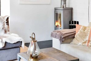 Una sala acogedora con una chimenea moderna, un sofá mullido y una lámpara decorativa.