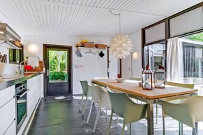Eine moderne Küche mit weißen Schränken, einem Holztisch und einem großen Fenster.