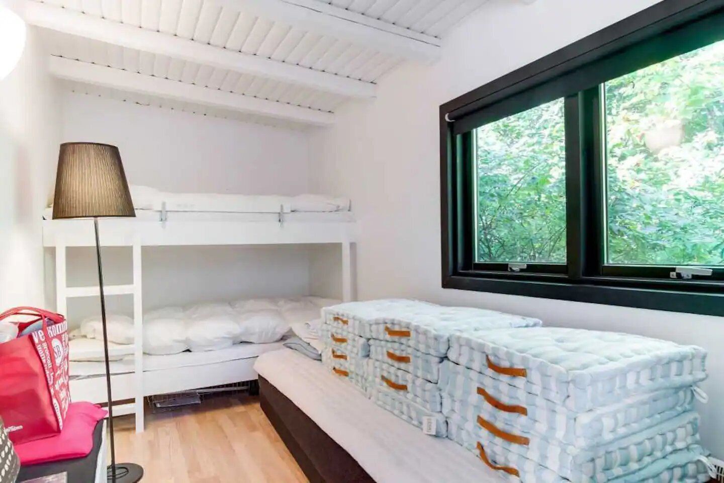 Ein Schlafsaalzimmer mit einem Fenster, einer Lampe und einem Stapel Kissen.