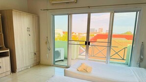 Habitación de hotel con dos camas, un armario y un balcón con vista a la ciudad.