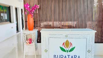 A reception desk with a logo labeled "BUPATARA" and a decorative vase with pink flowers.