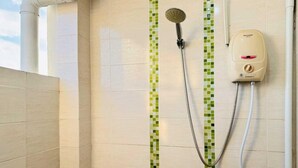 Un área de ducha con cabezal de ducha manual, un cabezal de ducha manual montado en la pared y un accesorio de ducha manual.