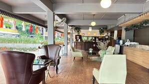 A modern cafe with leather chairs, a bar area, and a view of greenery outside. - Elegant Deluxe DBL  Stylish Chiangmai Comfort (Chiang Mai)
