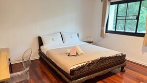 A neatly made bed with a wooden headboard, a bedside table, and a chair. - Elegant Deluxe DBL  Stylish Chiangmai Comfort (Chiang Mai)