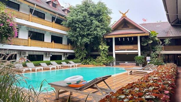 A hotel with a swimming pool, lounge chairs, and a traditional building with a golden roof. - Private Double with Shared Bath | Budget Pick (Chiang Mai)