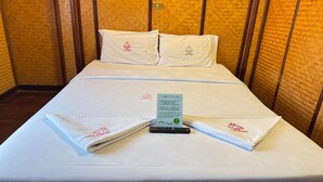A neatly made bed with white linens and pillows, a remote control, and a message card on the bed. - Private Double with Shared Bath | Budget Pick (Chiang Mai)