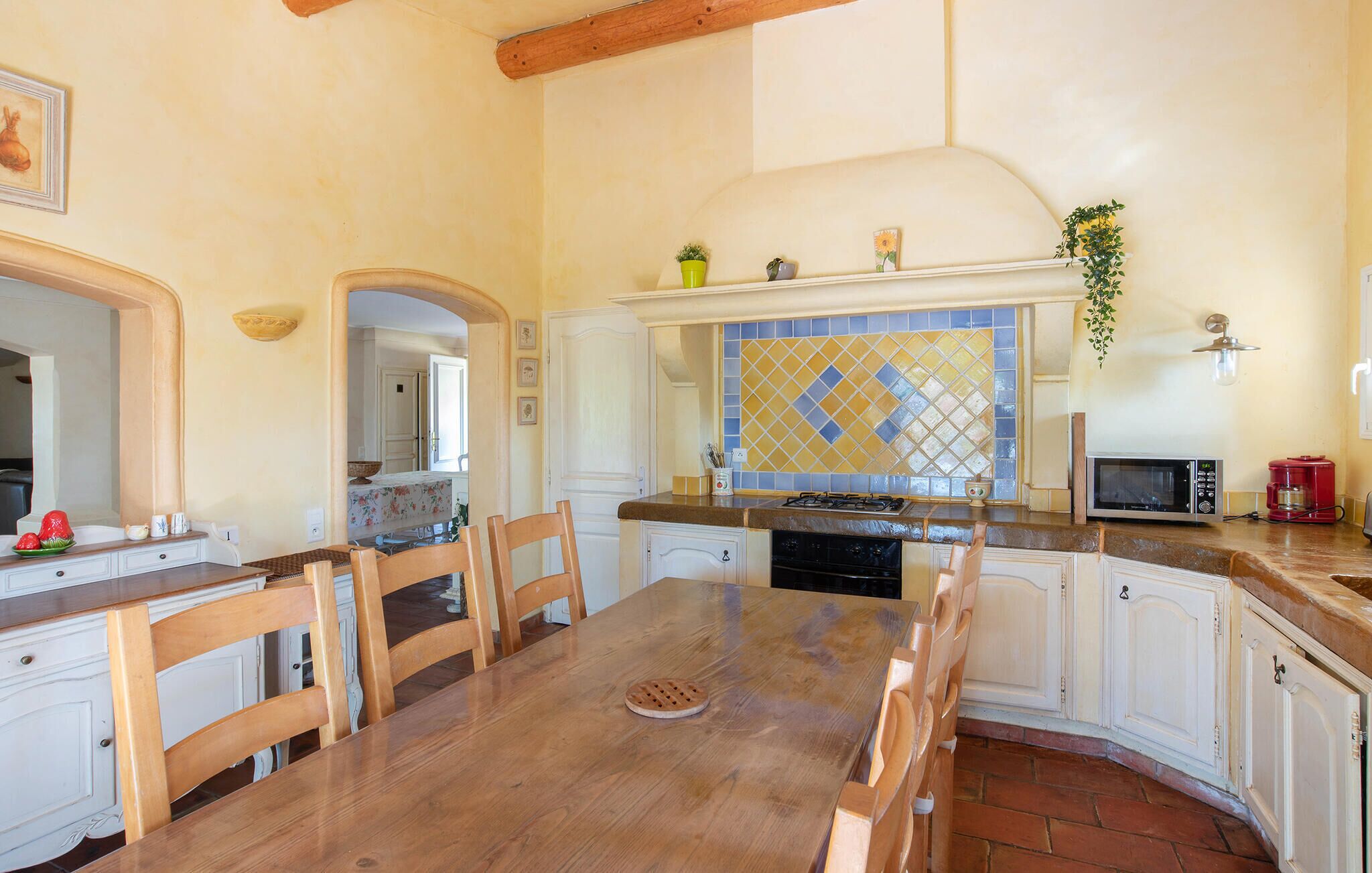 A kitchen with a wooden table, chairs, a stove, and a microwave.