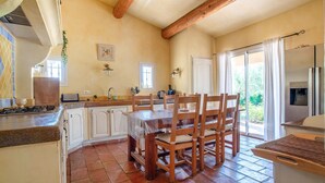 Une cuisine équipée d’une table à manger, de chaises, d’une cuisinière et d’un réfrigérateur.
