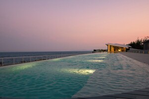 Una piscina con vista al océano al anochecer.
