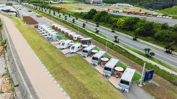 A campsite with RVs parked in rows, a highway in the background, and a bridge.