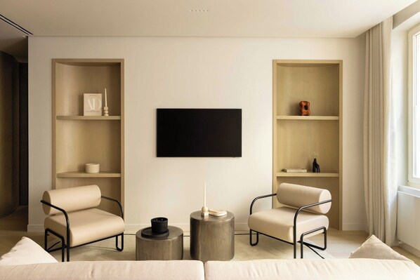 A modern living room with two armchairs, a coffee table, and built-in shelving.