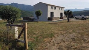 Una casa de un piso con fachada blanca, un camino de entrada y una camioneta estacionada.