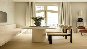 A modern living room with a round dining table, a sofa, and a TV mounted on the wall. - Luxury flat -2BR/6P- Madeleine/Saint Honore (Paris)