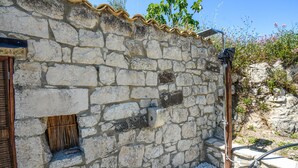 A stone building with a small window, a wooden door, and a metal shower structure. - Stunning home in Monterosso Almo (Monterosso Almo)