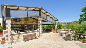 A covered outdoor patio with stone walls, a wooden bench, and potted plants. - Stunning home in Monterosso Almo (Monterosso Almo)
