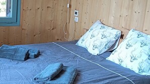 Un dormitorio con paneles de madera, una cama, almohadas, una lámpara de noche y un aplique colgante.