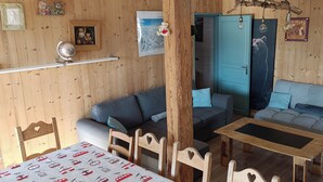 Una habitación acogedora con detalles de madera, una puerta azul, un sofá gris, una mesa de madera y un globo terráqueo en un estante.