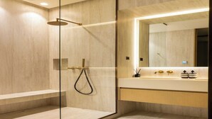 A modern bathroom with a glass-enclosed shower, a vanity with a mirror, and a light fixture above the mirror.
