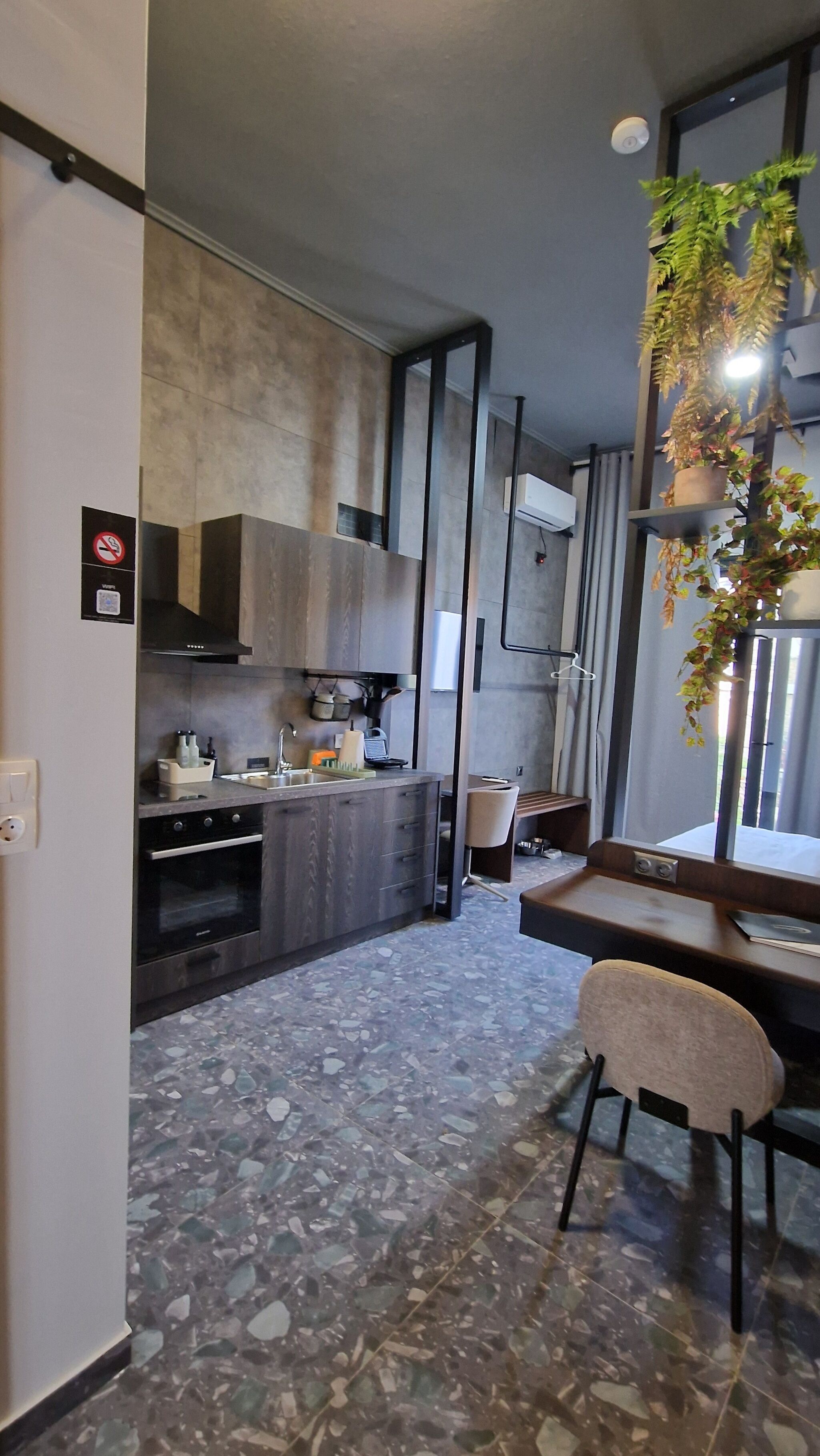 Una cocina moderna con encimera de granito, horno empotrado y comedor con una silla y mesa.