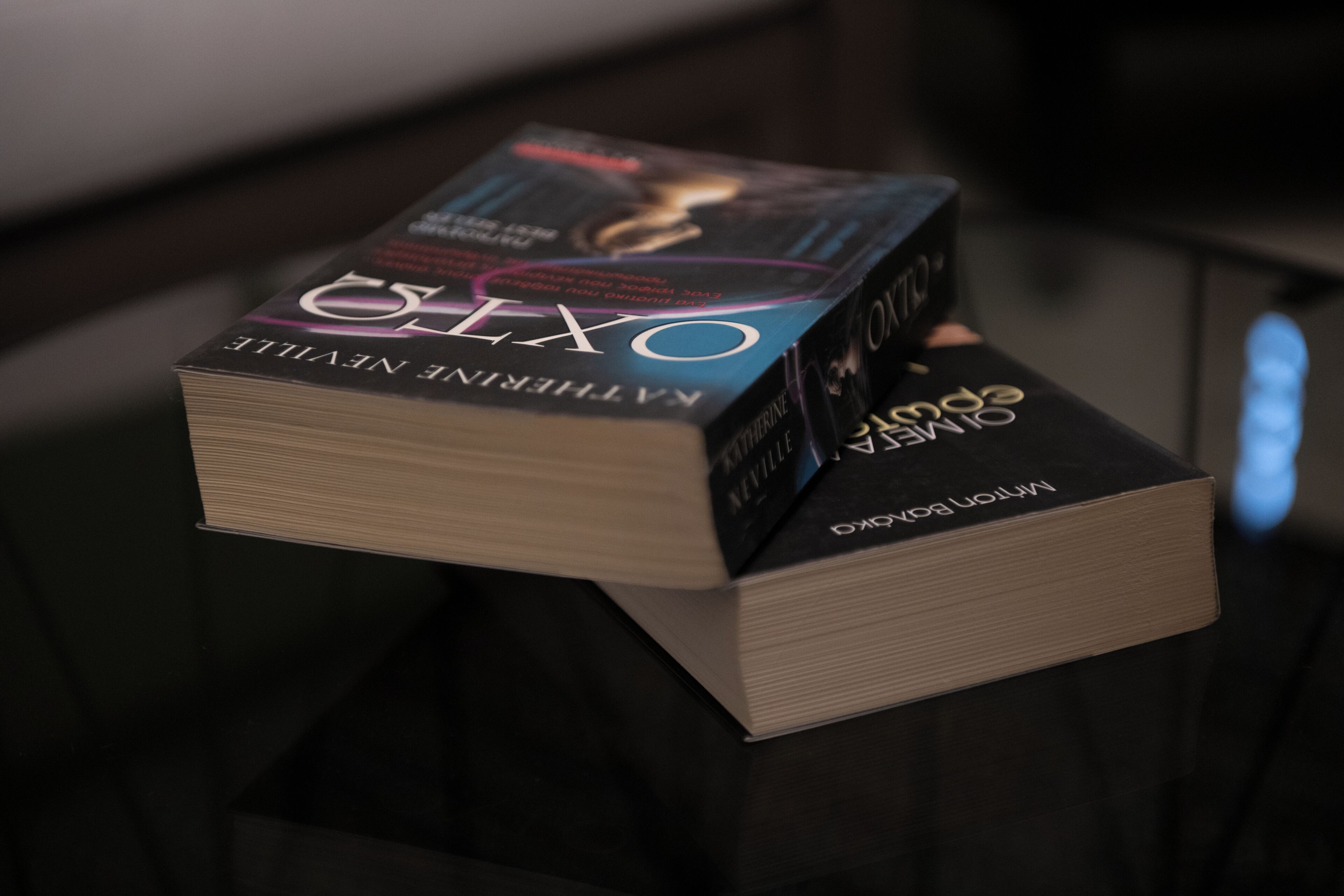 A stack of books titled 'OXYGEN' and 'INTERNATIONAL NEWS' on a reflective surface.