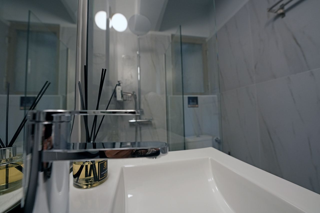 Un bagno moderno con cabina doccia in vetro, un lavandino bianco e uno specchio.