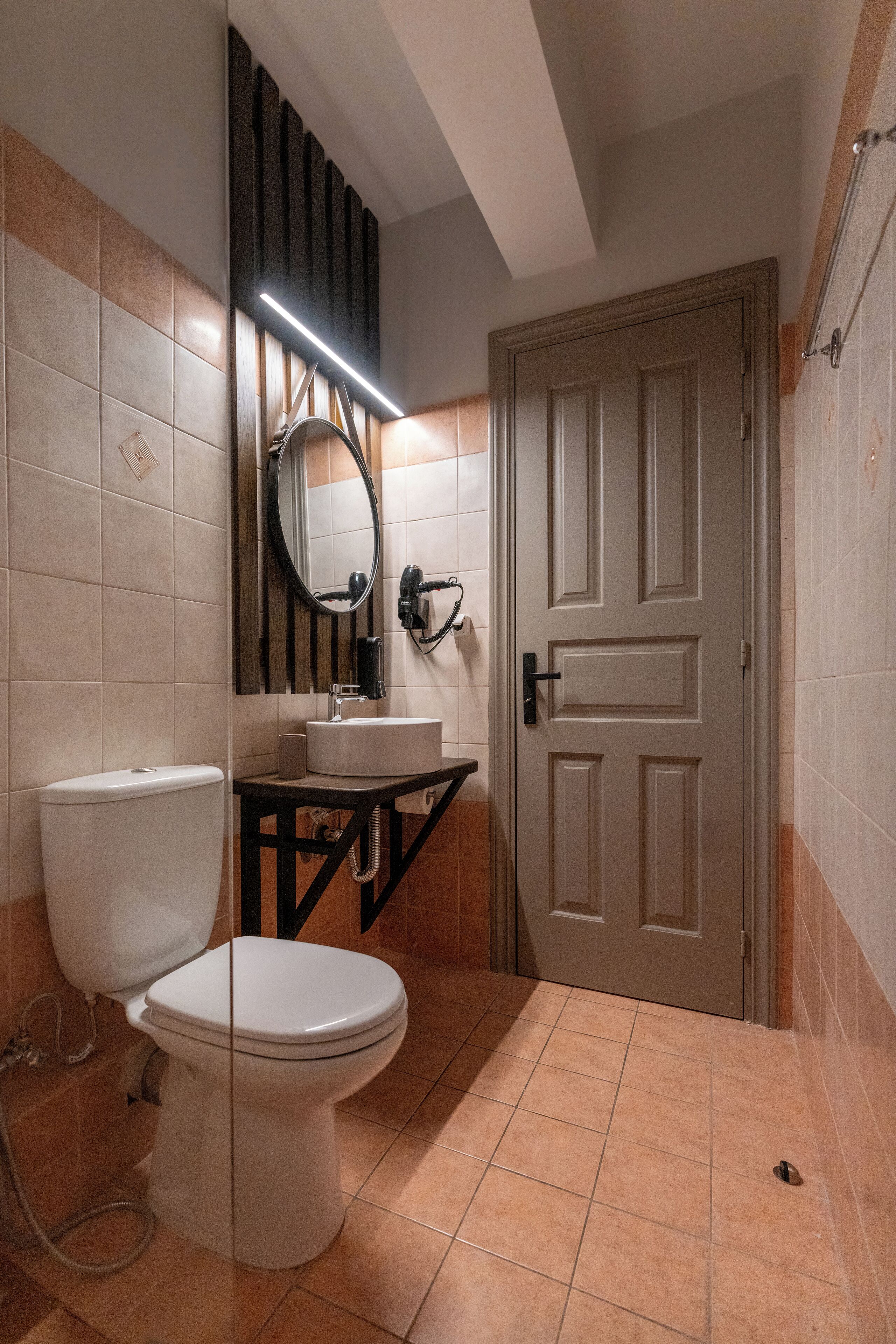 A bathroom with a toilet, sink, mirror, and a door.