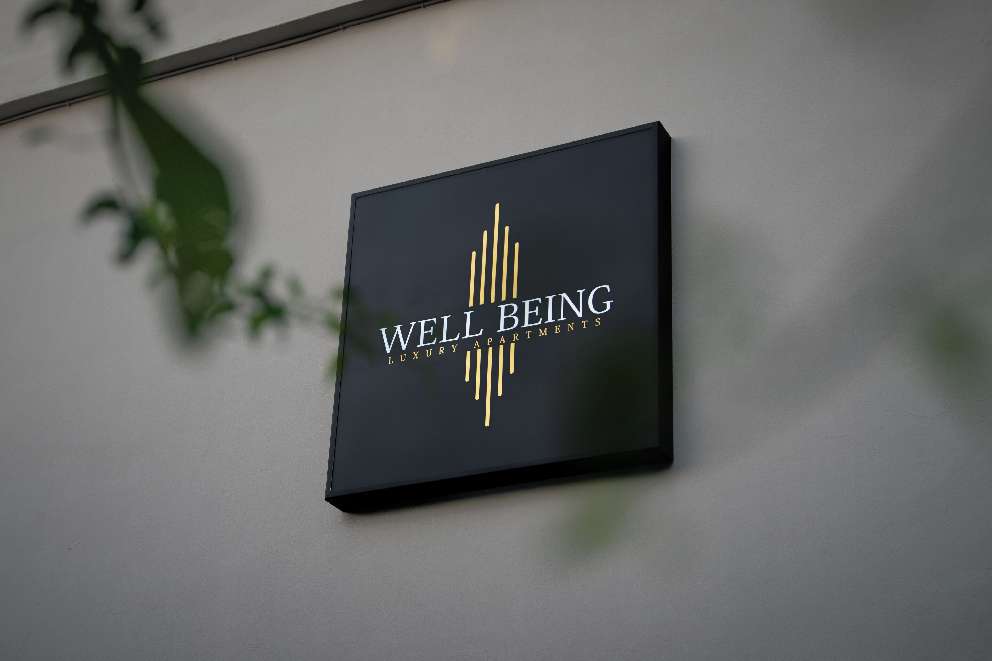 A black sign with gold lettering reading "WELL BEING LUXURY APARTMENTS".