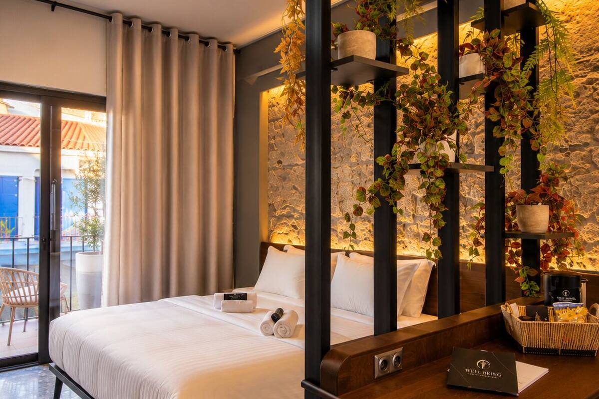 A modern hotel room with a bed, a desk, and a view of the outside.