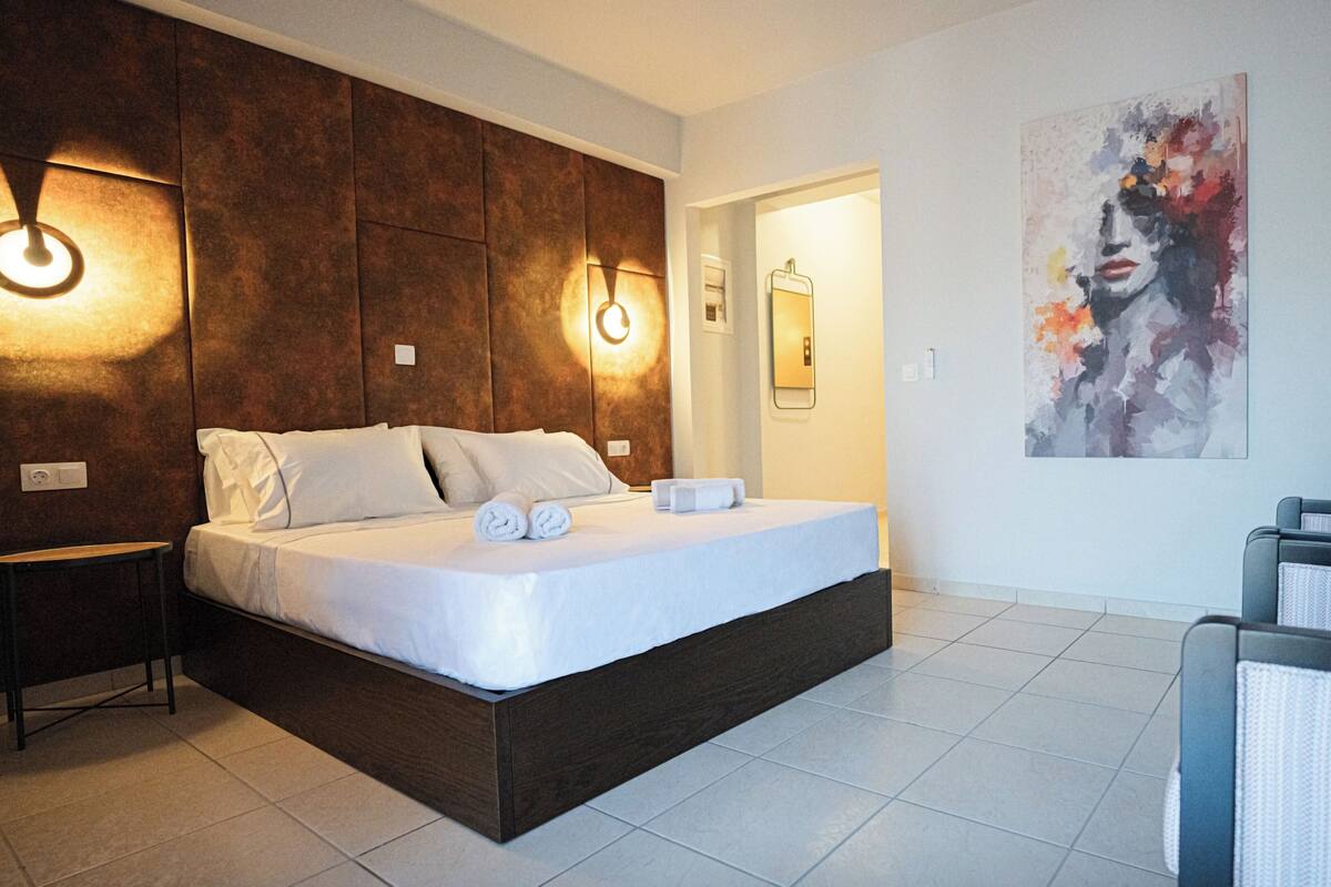 A modern hotel room with a large bed, two bedside tables, and a wall-mounted light fixture.
